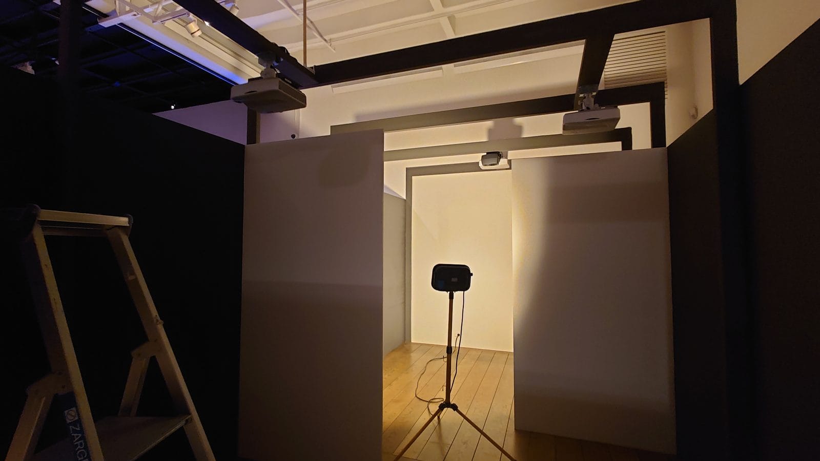 Oppsett av kunstinstallasjonen med projektorer i taket over hvite vegger