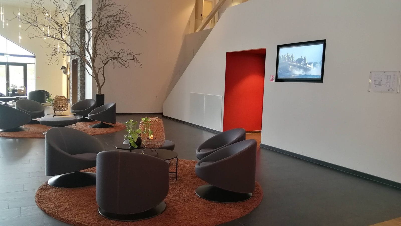 Lobby med loungestoler og en innfelt skjerm som viser video av en RIB-båt
